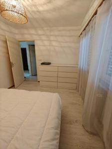 een witte slaapkamer met een bed en een ladekast bij F2 cozy centre ville proche bale et tram in Saint-Louis +10 foto's