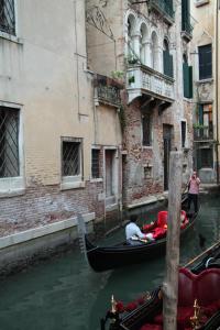 un par de personas en una góndola en un canal en Albergo al Tiepolo, en Venecia