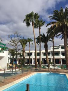 a pool with palm trees in front of a building at Paradise Club L28 & L29 in Puerto del Carmen