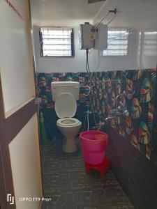 ein Badezimmer mit einem WC und einem roten Eimer in der Unterkunft guest house Akshay in Akalkot