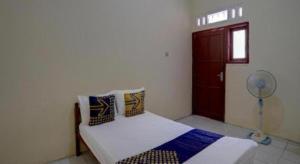 1 dormitorio con 1 cama con ventilador y puerta en Hotel O Sunyoto Homestay Syariah, en Banjarsalero