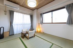 a living room with a chair and large windows at AMP FLAT MOMOCHi in Fukuoka