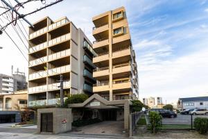 a tall apartment building with a parking lot at AMP FLAT MOMOCHi in Fukuoka