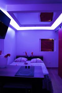 ル・ゴジエにあるLove Room Ô Fruit de la passionの洗面台と紫色の照明が付いたベッドのある寝室 +13枚の写真