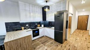 a kitchen with white cabinets and a black refrigerator at GOLD APARTAMENT Ząbki in Ząbki