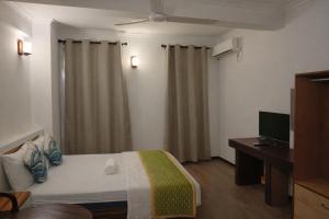 a bedroom with a bed and a desk and a television at Male City Stay in Male City