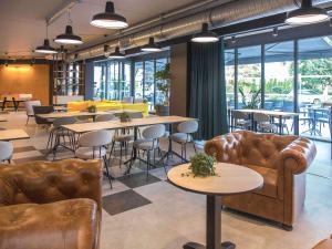 Un restaurante con sofás, mesas y sillas. en ibis Styles Bâle-Mulhouse Aéroport, en Blotzheim