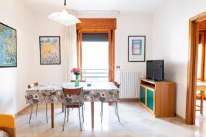 una sala da pranzo con tavolo, sedie e TV di Silver Bay Apartments a Porto Cesareo