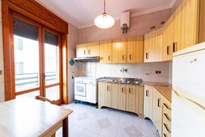 una cucina con mobili in legno e un frigorifero bianco di Silver Bay Apartments a Porto Cesareo