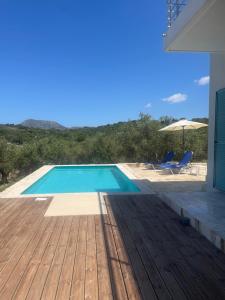 una piscina con terrazza in legno e alcune sedie di villa Elaionas a Tsivarás