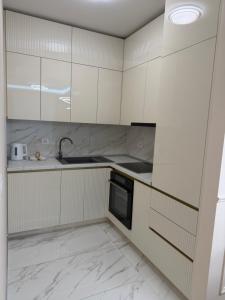 a kitchen with white cabinets and a sink and a dishwasher at Palata Royal Banja Luka Luxury Apartment in Banja Luka +6 photos