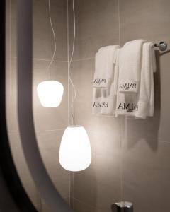 a bathroom with two lights and towels on a wall at Grand Inn Hotel in Bangkok