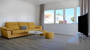 sala de estar con sofá amarillo y TV en Deva Beach Boutique Apartments, en San Fernando