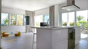 una cocina con encimeras y ventanas blancas y una mesa en Deva Beach Boutique Apartments, en San Fernando