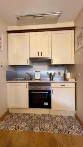 una cucina con armadietti bianchi e lavastoviglie nera di Flor de Hielo a Candanchú