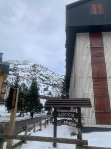a sign in front of a building with a snow covered mountain at Flor de Hielo in Candanchú