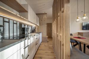 a kitchen with white cabinets and a wooden floor at Tieja Panoramic Lodge in Selva di Val Gardena