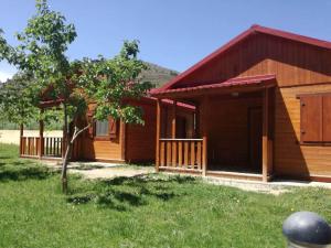 una casa in legno con un albero di fronte di Camping Las Aguas 