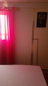 a bedroom with a bed and a window with red curtains at Mïkao vëga in Yaoundé