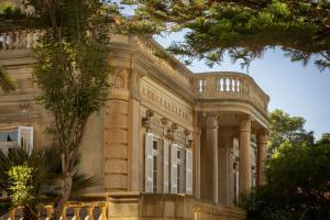 a large stone building with columns and trees at Corinthia Palace Malta in Attard