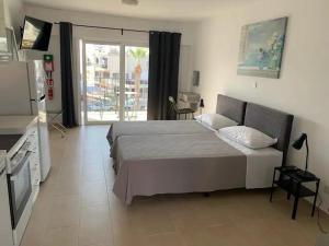 a bedroom with a large bed and a television at Rimini Balcony Studios - Steps from the Sea in Paphos