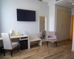 Zimmer mit einem Schreibtisch und Stühlen sowie einem TV an der Wand in der Unterkunft Le Grand Hôtel de Thiès in Thiès