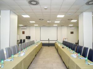 einen Konferenzraum mit Tischen und Stühlen und einem weißen Bildschirm in der Unterkunft Le Grand Hôtel de Thiès in Thiès