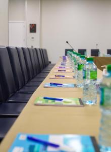 ein langer Tisch mit Stiften und Wasserflaschen in der Unterkunft Le Grand Hôtel de Thiès in Thiès