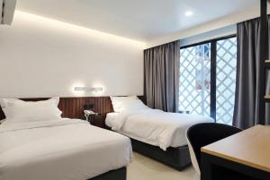 a hotel room with two beds and a window at Grand Inn Hotel in Bangkok