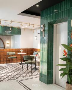 a waiting room with green tiled walls and tables at Grand Inn Hotel in Bangkok