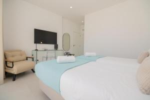 een witte slaapkamer met een groot bed en een stoel bij Sirius House in Guia