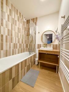 ein Badezimmer mit Badewanne, Waschbecken und Spiegel in der Unterkunft L'Oranger bleu in Royan + 19 Fotos