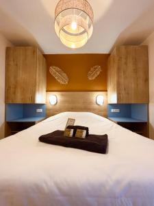 ein Schlafzimmer mit einem großen weißen Bett mit einem Kronleuchter in der Unterkunft L'Oranger bleu in Royan