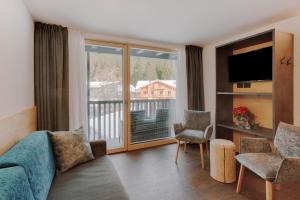a living room with a couch and a large window at Alpen Hotel Vidi in Madonna di Campiglio