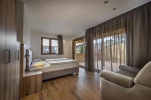 a bedroom with a bed and a chair and a window at Tieja Panoramic Lodge in Selva di Val Gardena