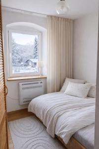 ein Schlafzimmer mit einem weißen Bett und einem Fenster in der Unterkunft Apartament z kominkiem in Jugów