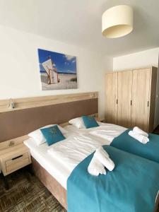 2 letti in una camera da letto con lenzuola e asciugamani blu di Apartament 301 Casa Bahia a Grzybowo