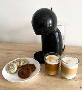 una macchinetta del caffè, un piatto di biscotti e una tazza di caffè di Apartament 301 Casa Bahia a Grzybowo