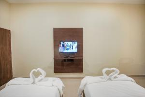 two swan beds in a room with a tv at Kayalresidency in Gopichettipālaiyam