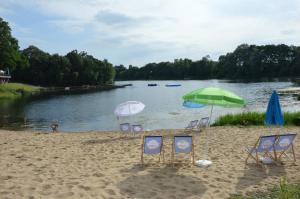 a group of chairs and umbrellas on a beach at Gruppenunterkunft am Waldsee in Krefeld