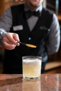 a man in a tuxedo is stirring a drink at Alpen Hotel Vidi in Madonna di Campiglio