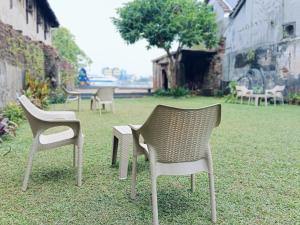 three chairs sitting on the grass in a yard at Creek Harbour Fort Kochi in Fort Kochi