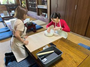 two women sitting at a table preparing food at Stay at matcha fields in Wazuka
