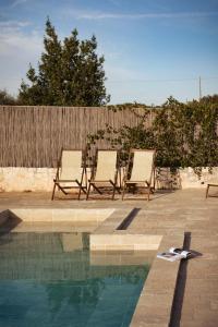 two deck chairs sitting next to a swimming pool at Regina di Ulivi in Ostuni