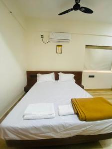 ein Schlafzimmer mit einem großen weißen Bett mit Deckenventilator in der Unterkunft Shubharambha Luxury Resort in Nagaon
