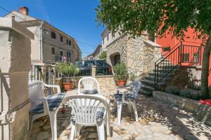 un grupo de sillas y mesas en un patio en Haus in Istrien direkt am Meer en Plomin