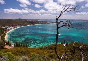 een uitzicht op een strand met turquoise water bij Saltbush Retreat in Nelson Bay