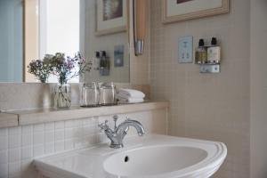 a white bathroom with a sink and a mirror at Braye Beach Hotel, Alderney in Alderney