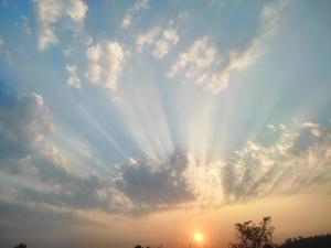 ein Himmel, in dem die Sonne durch die Wolken scheint in der Unterkunft Om sai villa in Neral