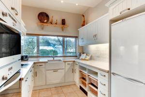 een keuken met witte kasten, een wastafel en een koelkast bij 4 Bed in Croyde oc-windy1 in Croyde +23 foto's